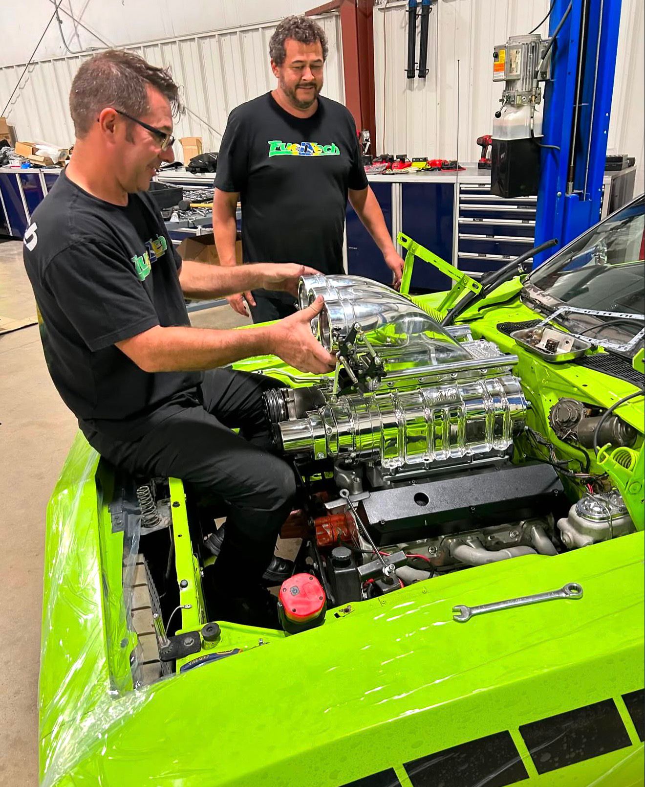 Technicians reviewing a green performance engine bay